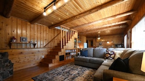 Een houten interieur met een trap, een bank en een vloerkleed.