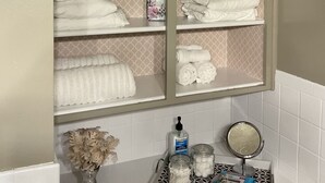 A bathroom vanity with a mirror, a towel rack, and a shelf with toiletries. - Cosy Home with Heated Pool (Edgewater)