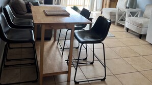 A compact living space with a dining table, chairs, a sofa, a TV, and a ceiling fan. - OCEANVIEW TOPSAIL ISLAND BEACH CONDO  1BR 1BA  KING BED SNOWBIRD FRIENDLY (North Topsail Beach)