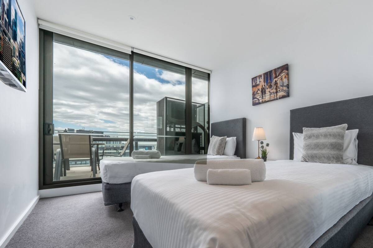 Ein modernes Hotelzimmer mit einem großen Bett, einem Balkon und Blick auf die Stadt.