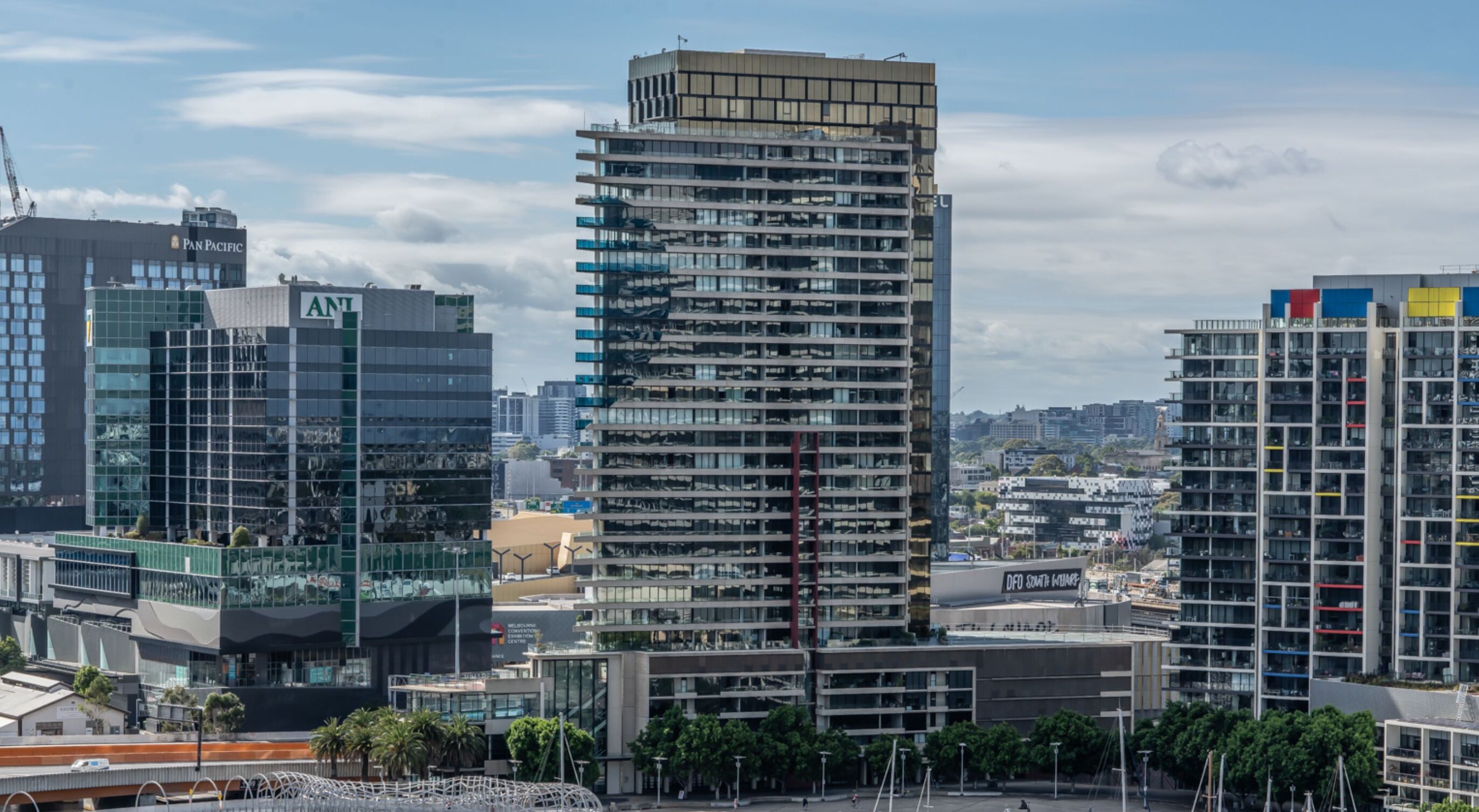 A high-rise building with a modern architectural design, featuring multiple balconies and a mix of glass and concrete facades.