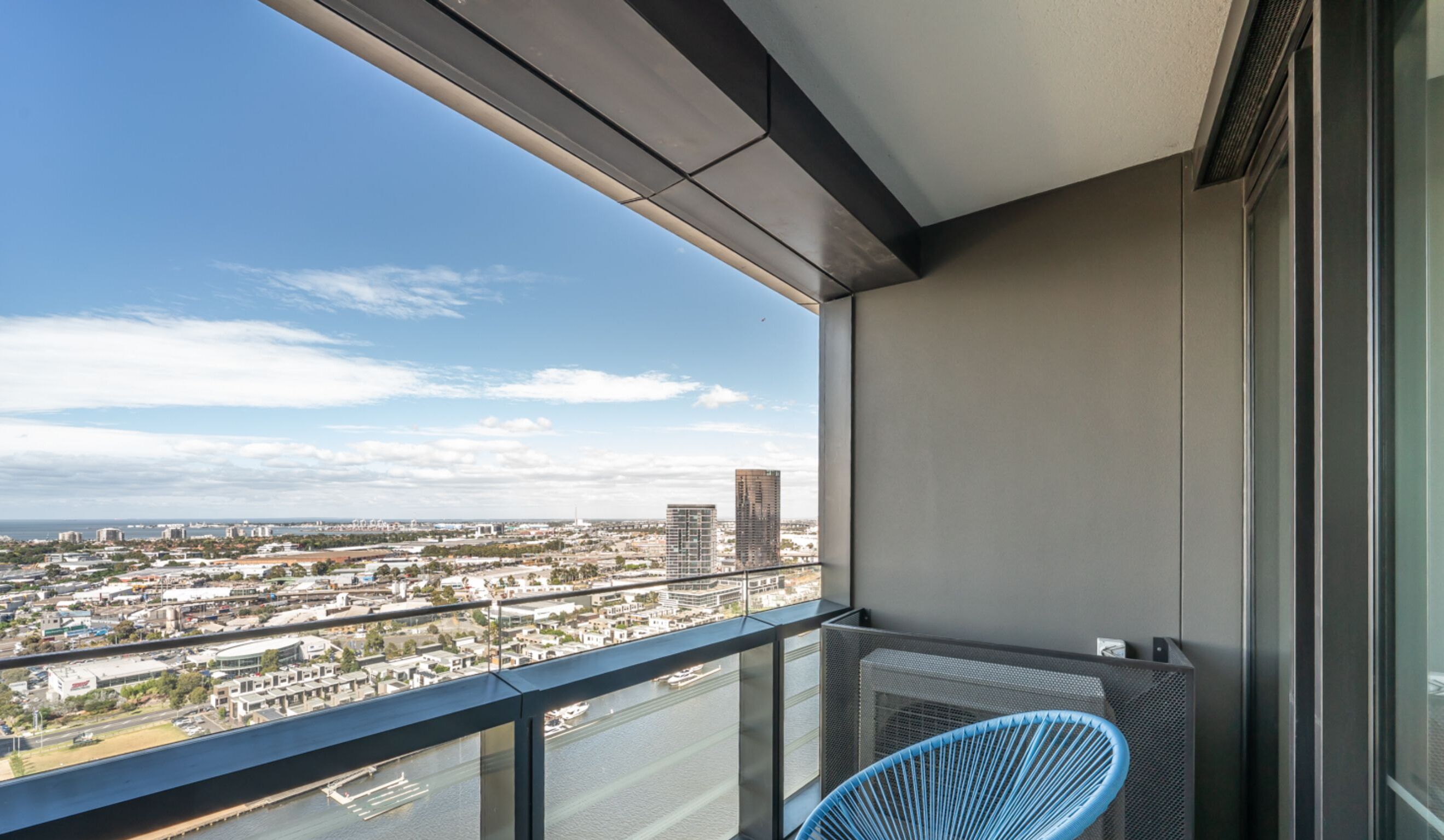 A balcony with a view of a cityscape, including buildings and a body of water.