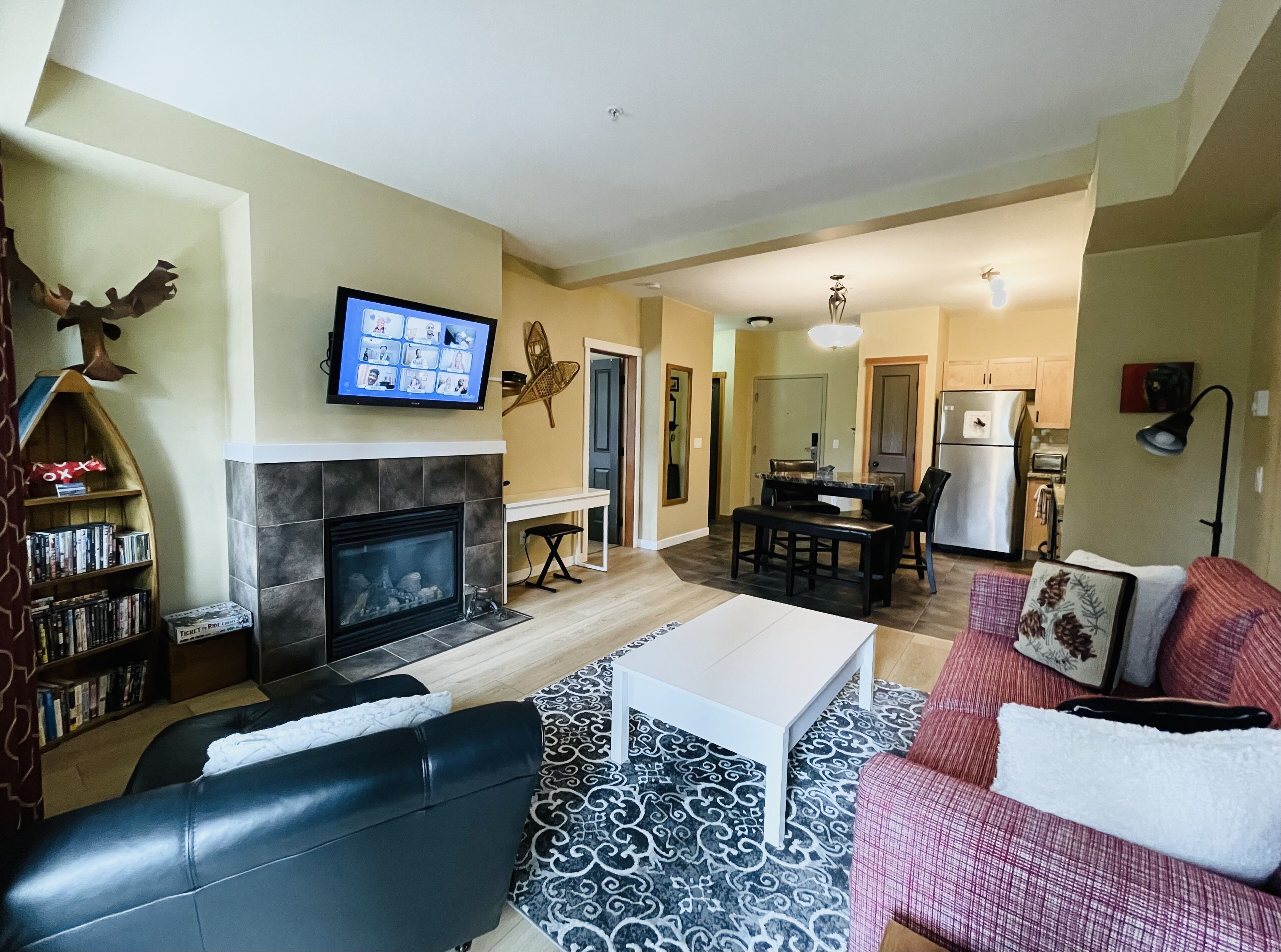 A living room with a fireplace, a television, a coffee table, a sofa, and a dining area with a table and chairs.