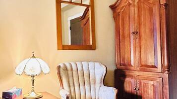 A room with a wooden cabinet, a chair, and a table with a lamp.