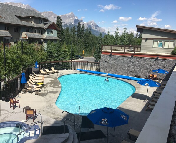 Relax by the pool surrounded by lounge chairs and umbrellas, with a hot tub nearby and breathtaking mountain views.