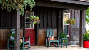 A wooden porch with two Adirondack chairs and a red door. - Bar 7 Ranch House - perfect for OHV travelers! (Meeker)