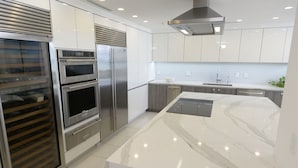Une cuisine moderne dotée d’appareils électroménagers en acier inoxydable, de meubles blancs et d’un plan de travail en marbre.