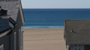 Une vue sur une plage, avec un bâtiment au premier plan et l’océan en arrière-plan.