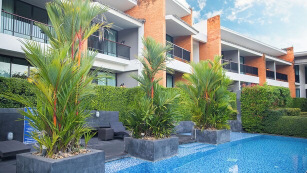 Um hotel moderno com piscina, área de estar externa e vegetação exuberante.