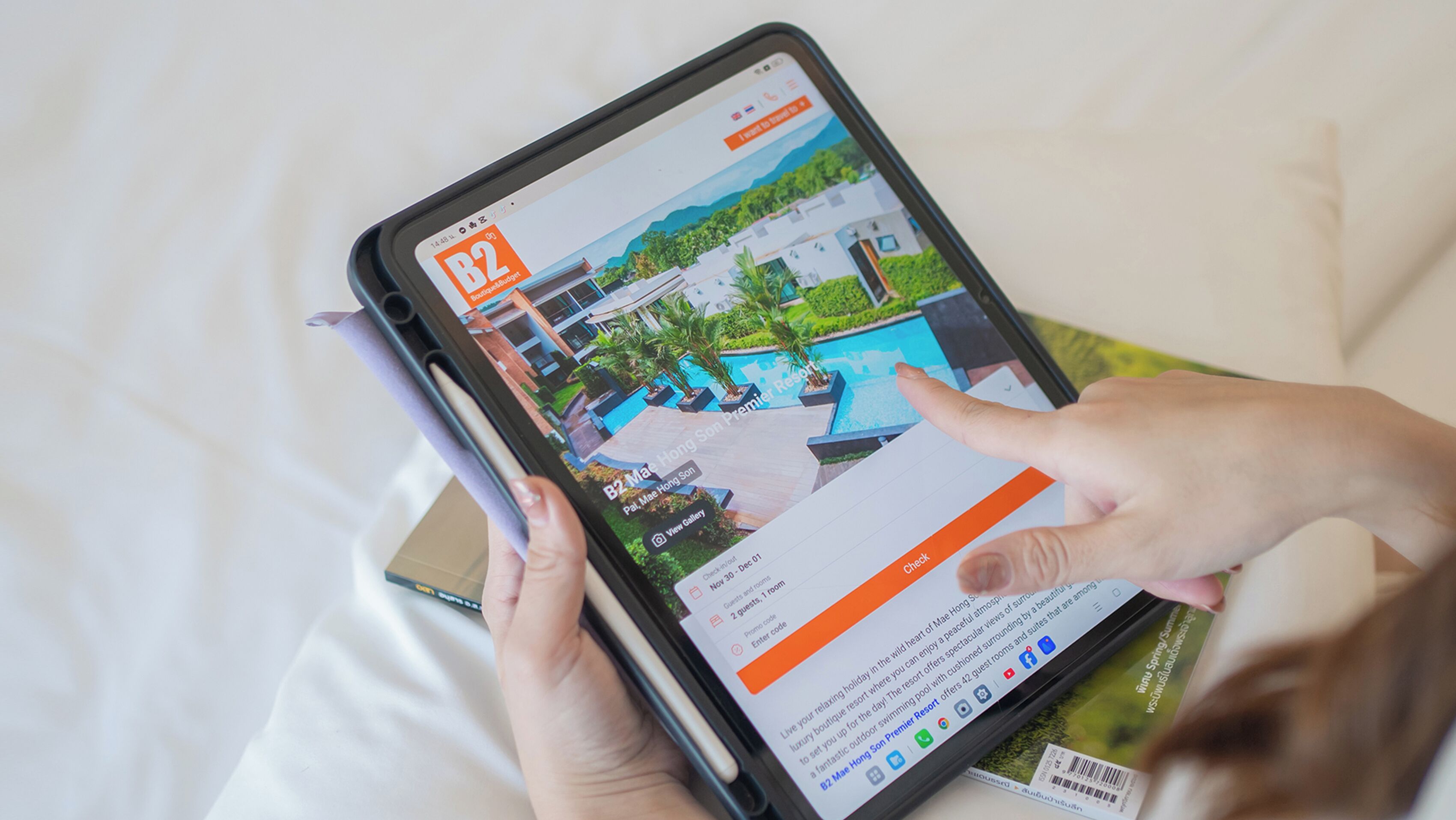 A tablet displaying a hotel website with a pool view, booking options, and a guest code entry field.