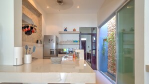 Une cuisine moderne dotée d’un îlot central, d’appareils électroménagers en acier inoxydable et offrant une vue sur l’extérieur grâce à une porte vitrée.