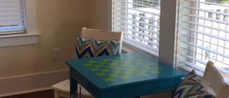 A dining area with a blue table and white chairs, featuring a decorative pillow on one chair.