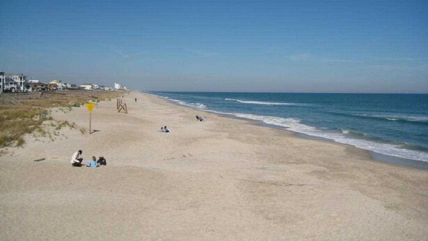 A beach with a clear sky, sandy shore, and a few people relaxing. - Beautiful newer home! 2 blocks to the boardwalk & 3 blocks to the beach!!!! (CAROLINA BEACH)