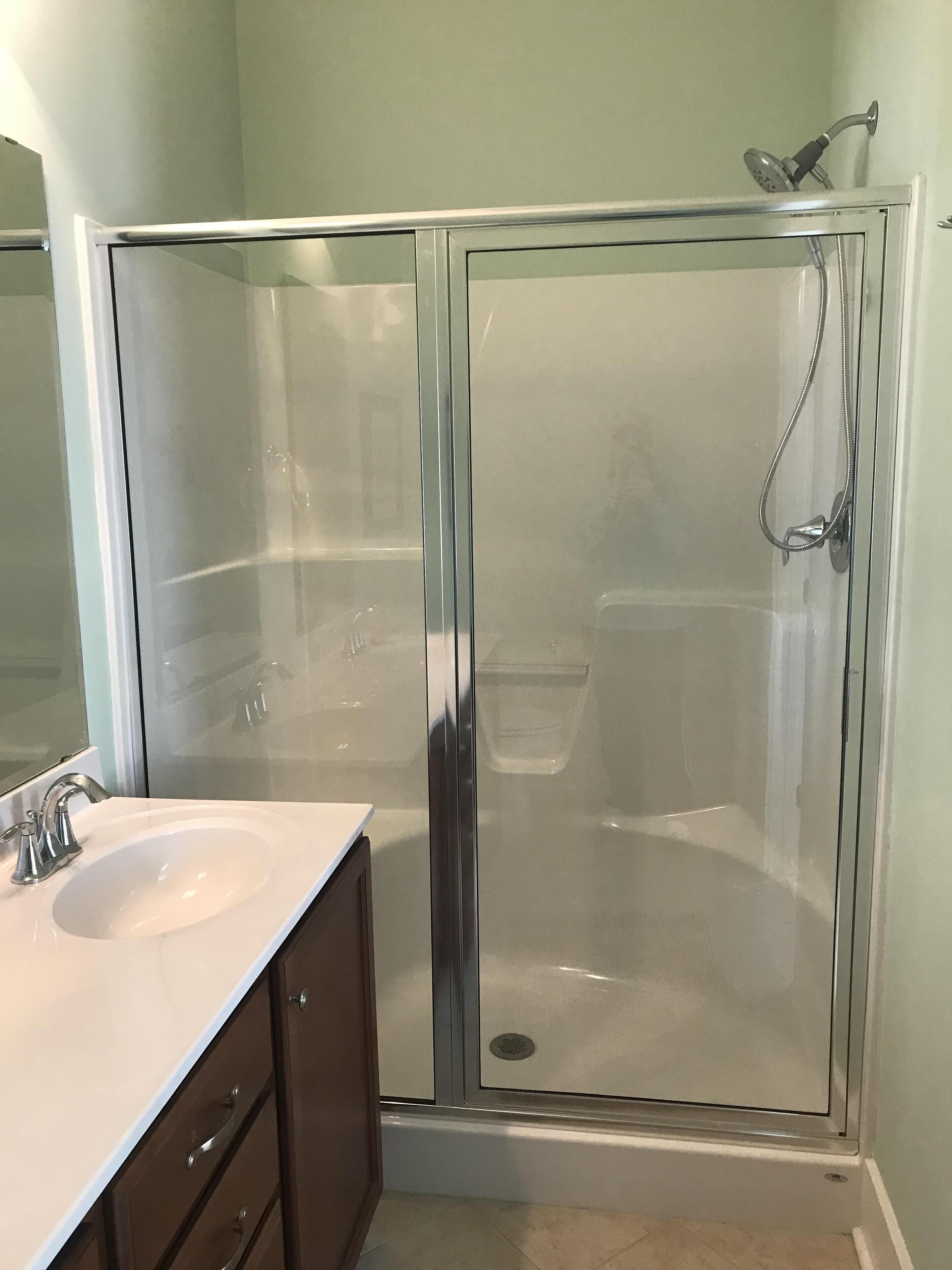 Un baño moderno con ducha de vidrio, un lavabo blanco y un espejo.