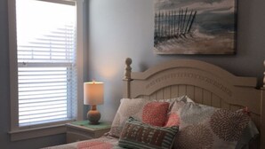 A bedroom with a bed, a nightstand, a lamp, a window with blinds, and a painting on the wall. - Beautiful newer home! 2 blocks to the boardwalk & 3 blocks to the beach!!!! (CAROLINA BEACH)