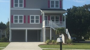 A two-story residential building with a front garage, a covered porch, and a small staircase leading to an upper level. - Beautiful newer home! 2 blocks to the boardwalk & 3 blocks to the beach!!!! (CAROLINA BEACH)