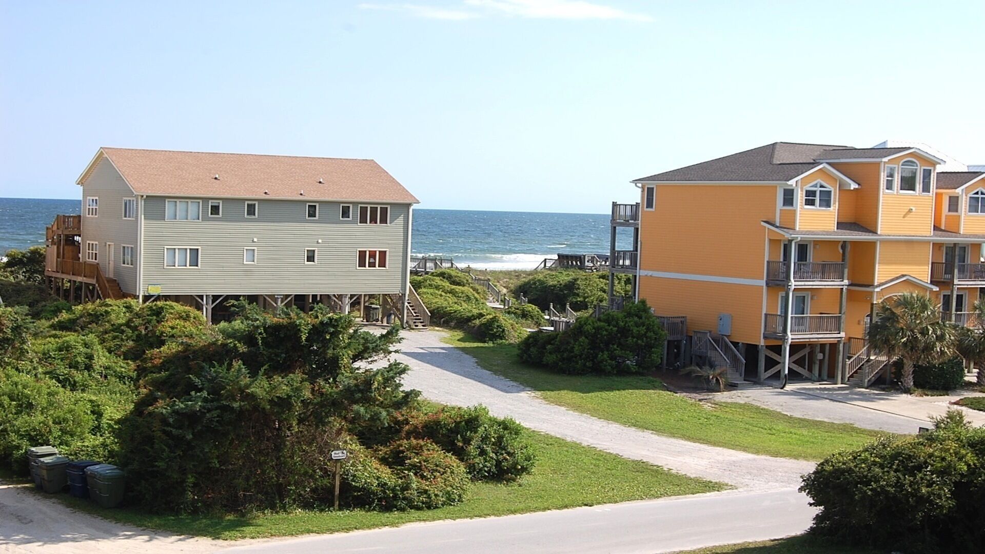 A coastal property with a wooden deck, a paved walkway, and a view of the ocean.