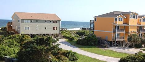 A coastal property with a wooden deck, a paved walkway, and a view of the ocean.