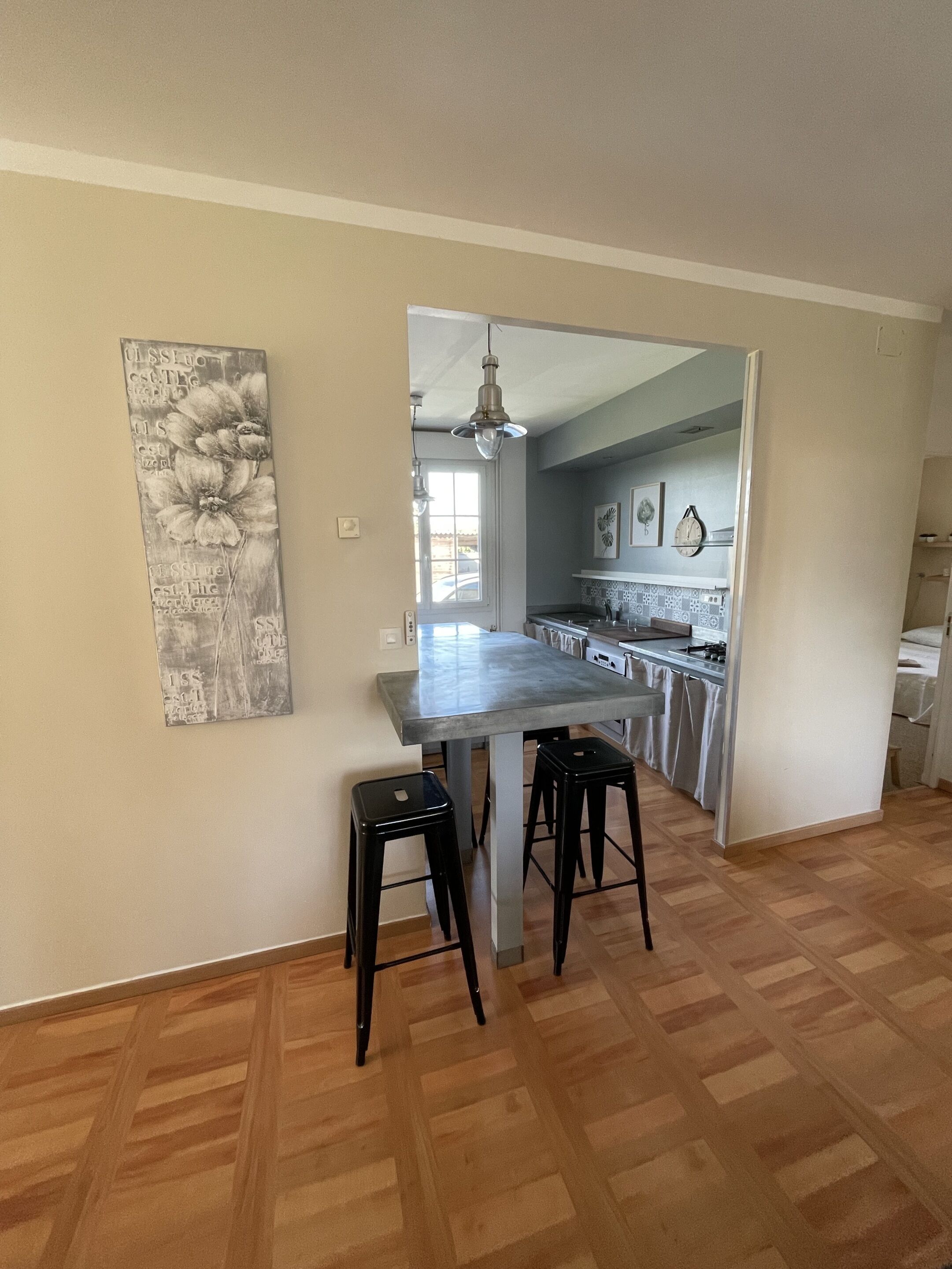 A spacious kitchen with a central island, two black stools, and a hanging light fixture.