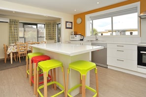 A modern kitchen with a central island, white cabinetry, and a large window providing natural light.