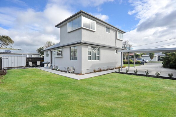 A modern two-story house with a flat roof, large windows, and a well-maintained lawn.