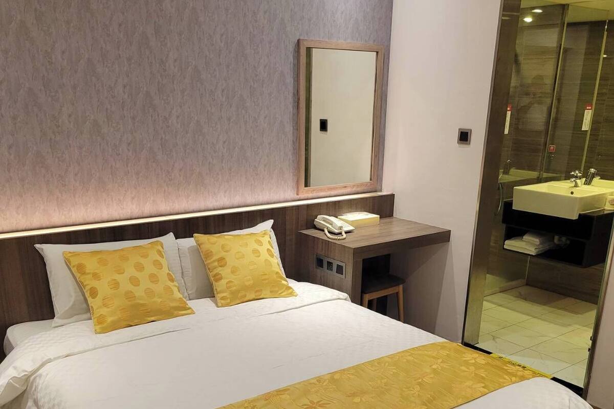 Una camera d'hotel con un letto grande, un comodino con il telefono e uno specchio sopra.
