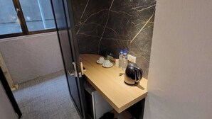 A compact kitchenette with a marble backsplash, a coffee maker, and a small table. - Attic Hotel (Taipei)