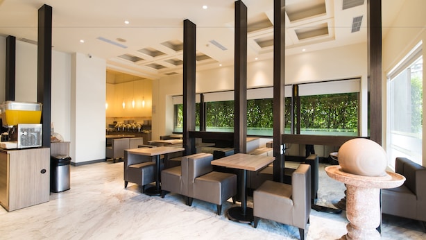 A modern restaurant with high tables and booths, a large window with a view of greenery, and a stone pedestal with a spherical object. - Kaohsiung The Rivero Hotel (Kaohsiung)