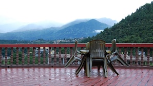 Une terrasse offrant une vue sur les montagnes et dotée d’une rambarde rouge.