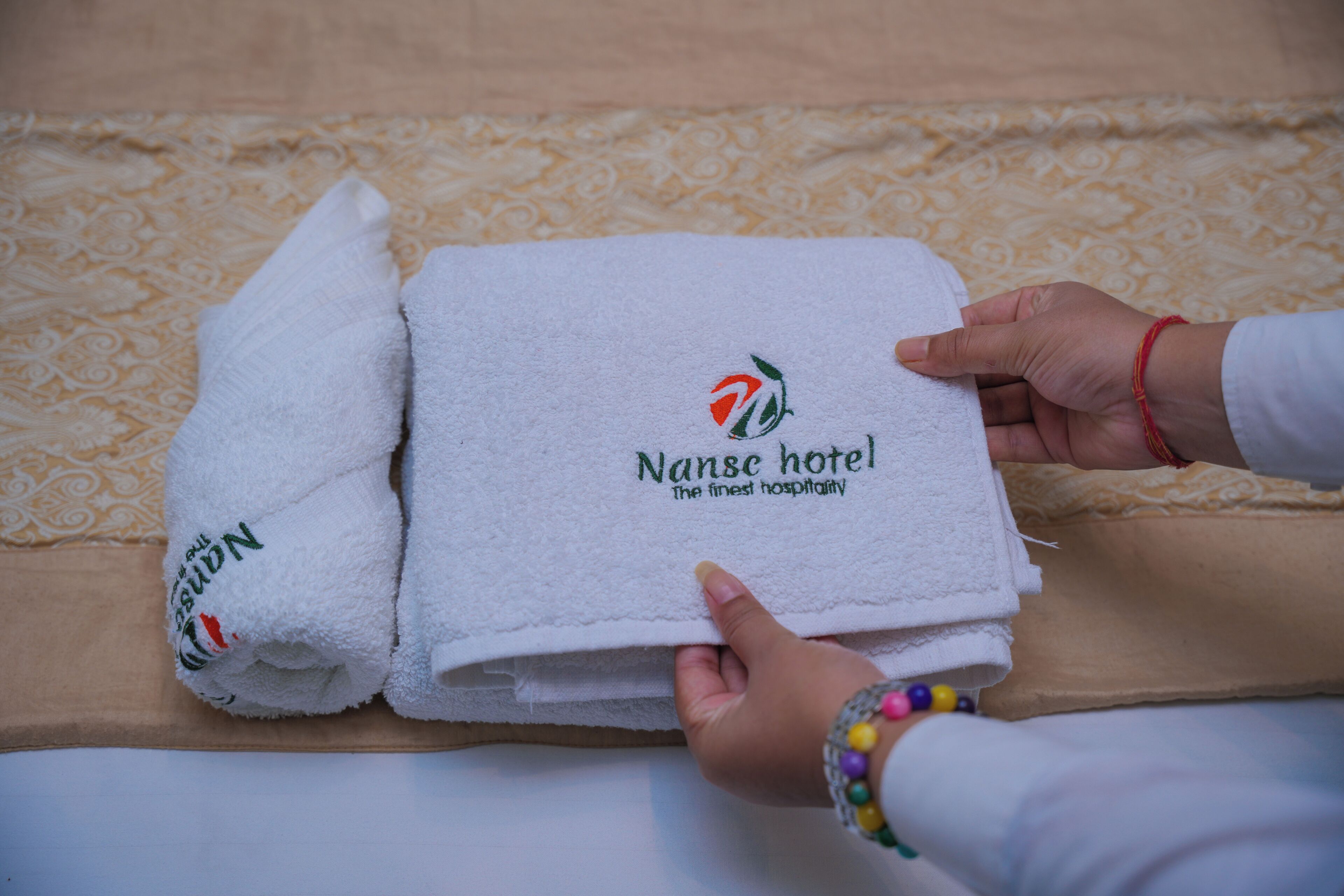 Una pila de toallas blancas con el logotipo y texto del hotel Nanse.