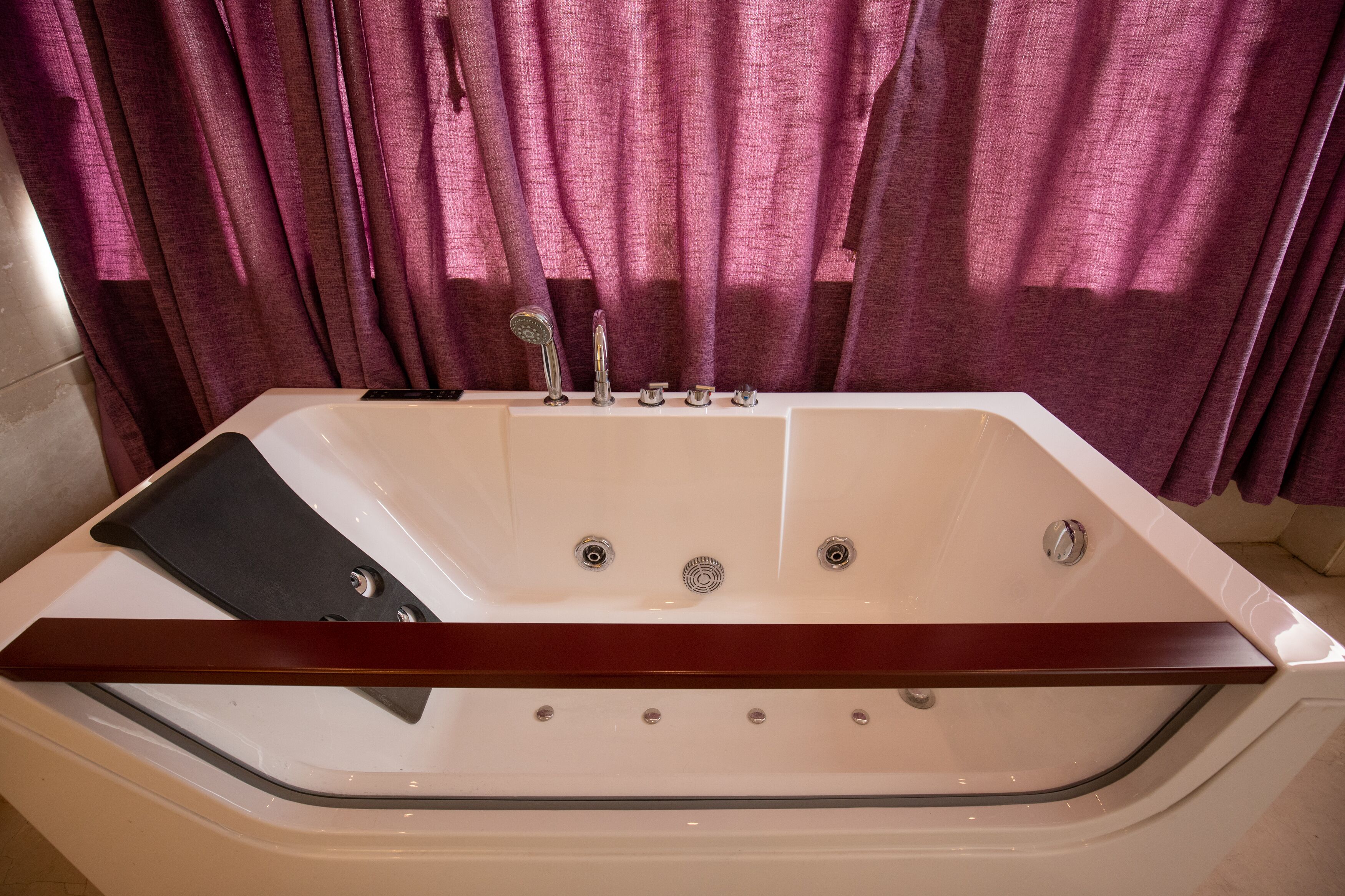 A modern bathroom with a freestanding bathtub, a wooden bath tray, and a showerhead.