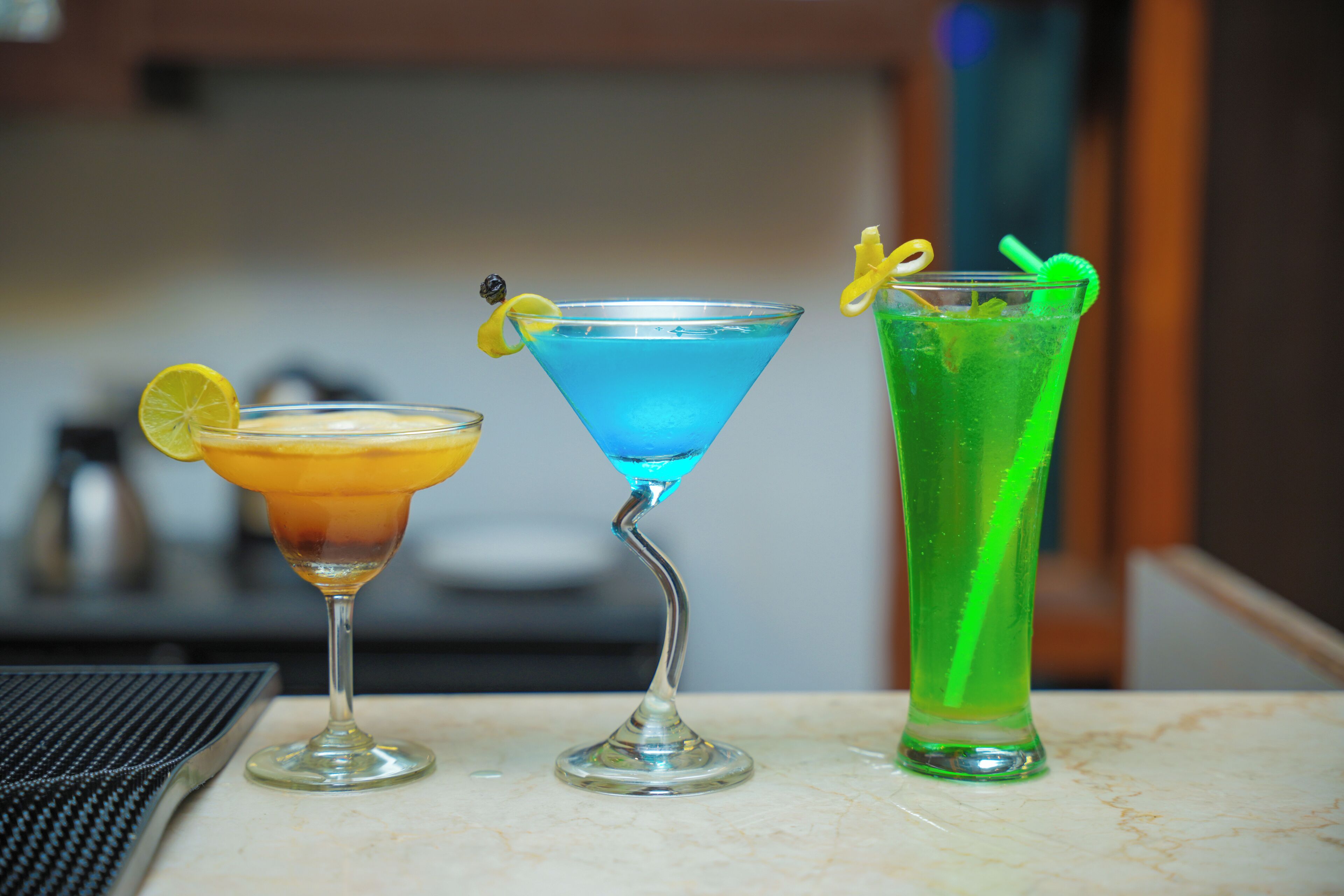 Three cocktails on a marble table with a blurred background.