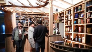 A bar area with wooden shelves stocked with various liquor bottles.