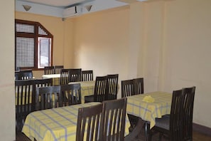 Un comedor con varias mesas y sillas, cada una cubierta con un mantel a cuadros amarillo y azul.