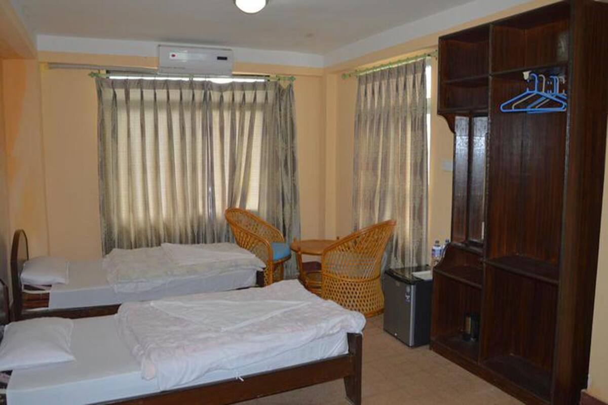 Een hotelkamer met twee bedden, een kast, een stoel en een kleine tafel.