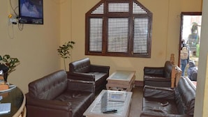 A living room with leather sofas, a coffee table, and a large window with a lattice design.