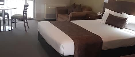 A hotel room with a large bed, a smaller bed, a desk, and a chair.