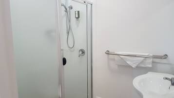 A bathroom with a glass-enclosed shower, a white sink, and a towel rack.