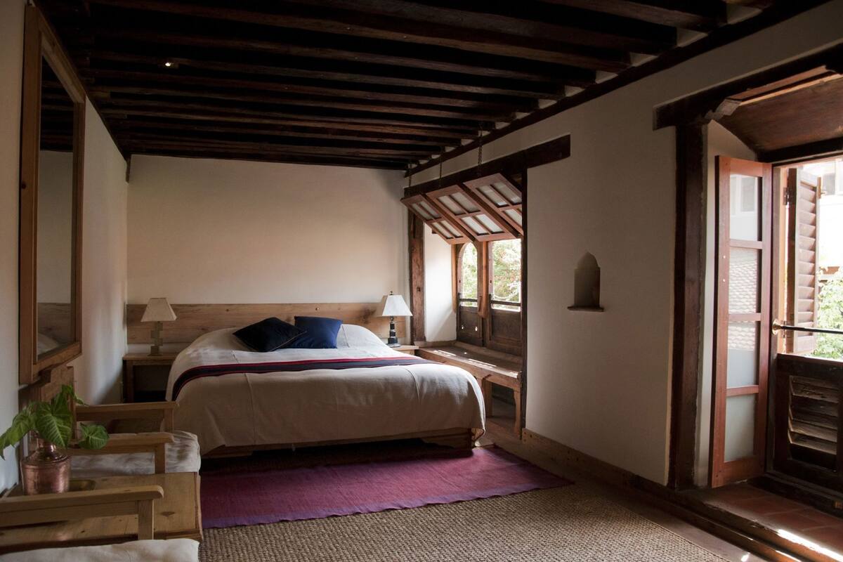 A bedroom with a bed, bedside tables, a lamp, a window, and a door.