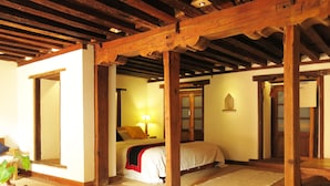 A traditional room with wooden beams, a bed with a red blanket, a lamp, and a mirror. - The Inn Patan (Lalitpur)