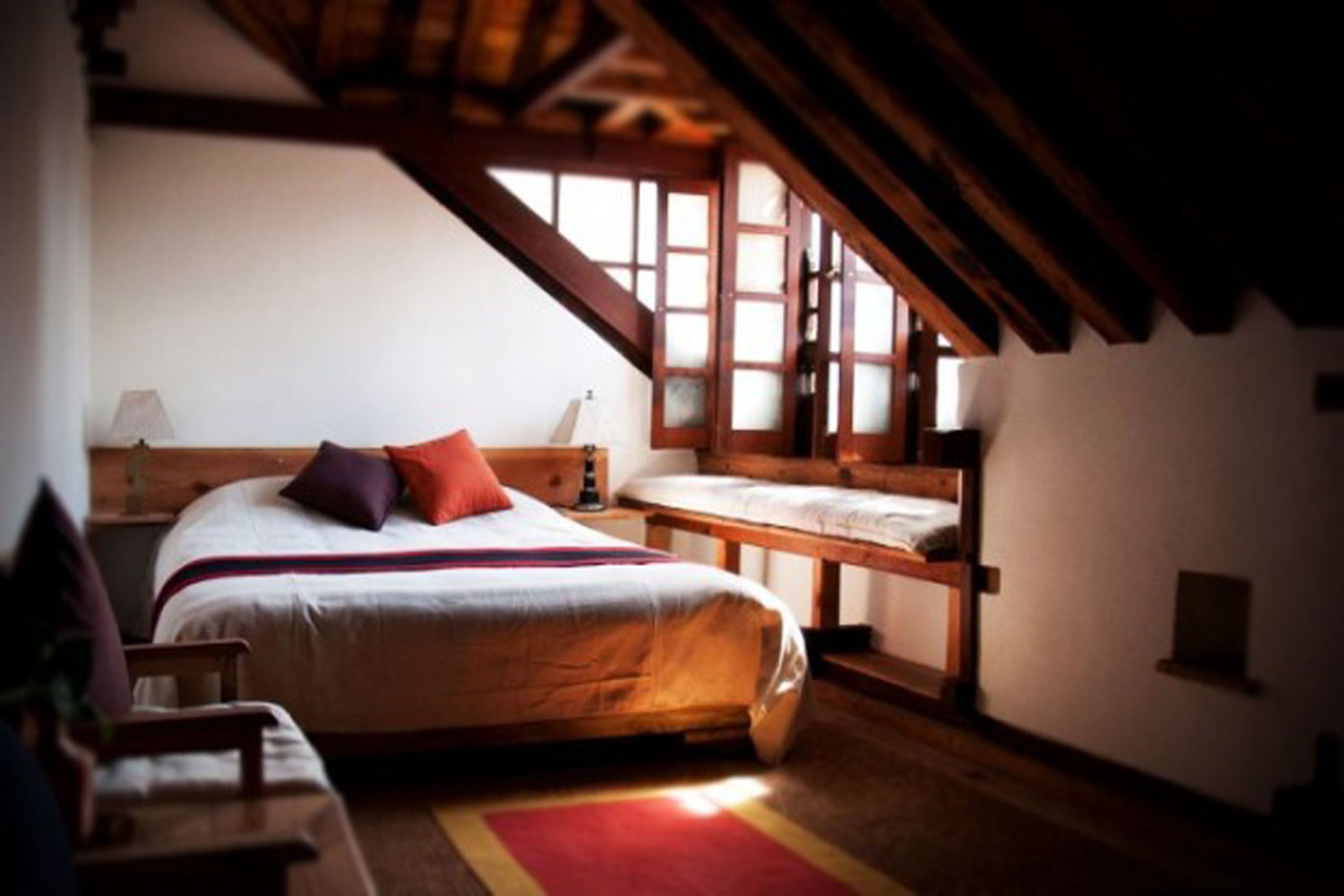 A cozy bedroom with a large bed, a smaller bed, and a wooden bench.