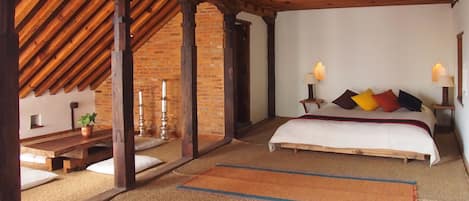 Un dormitorio con techo de madera, una cama con almohadas, una mesita de noche y una lámpara.