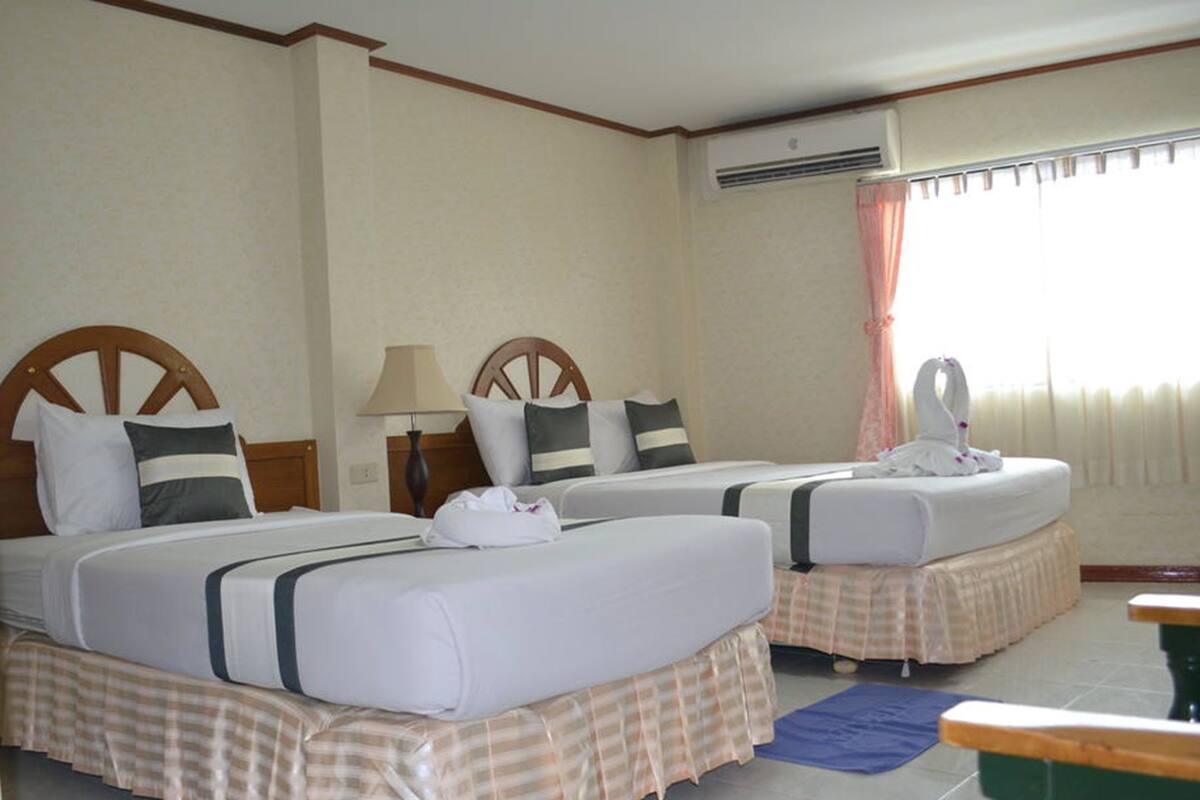 A hotel room with two beds, a desk, and a window with curtains.