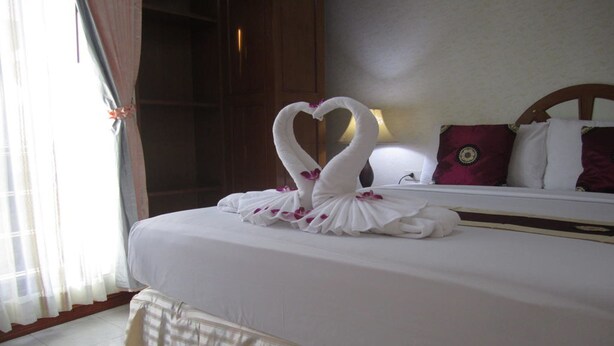 A hotel room with a neatly made bed, a large window with curtains, and a wooden headboard. - Natacha Hotel (Ko Phi Phi)