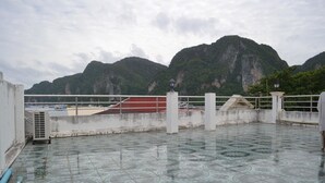 A rooftop terrace with patterned flooring, a railing, and a view of mountains. - Natacha Hotel (Ko Phi Phi)