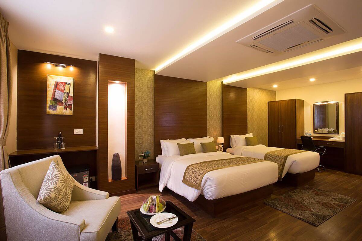 A hotel room with two beds, a sofa, a desk, and a bathroom.
