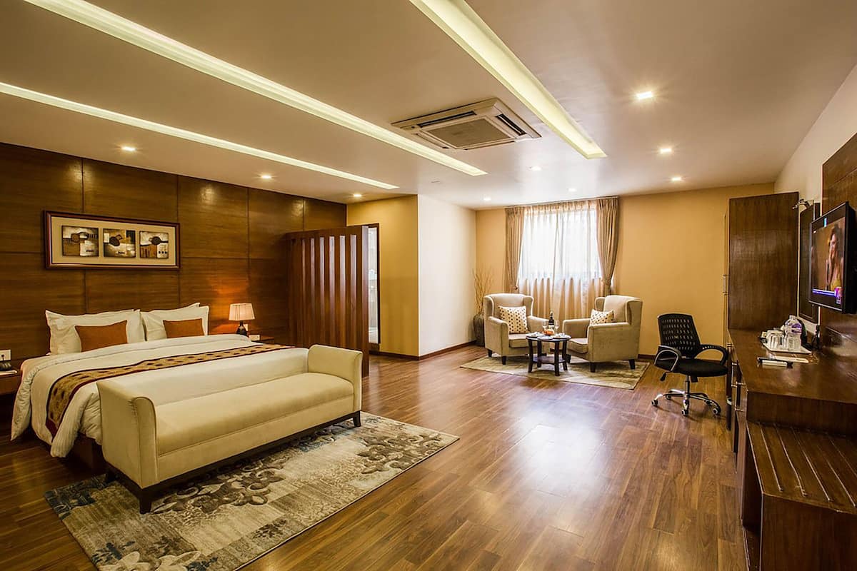 A hotel room with a large bed, a desk, a chair, and a TV.