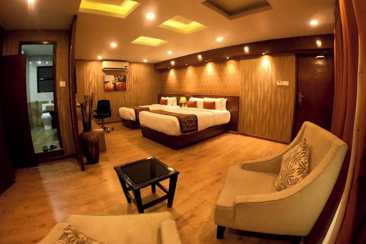 A hotel room with a large bed, two bedside tables, a sofa, a small table, and a mirror.