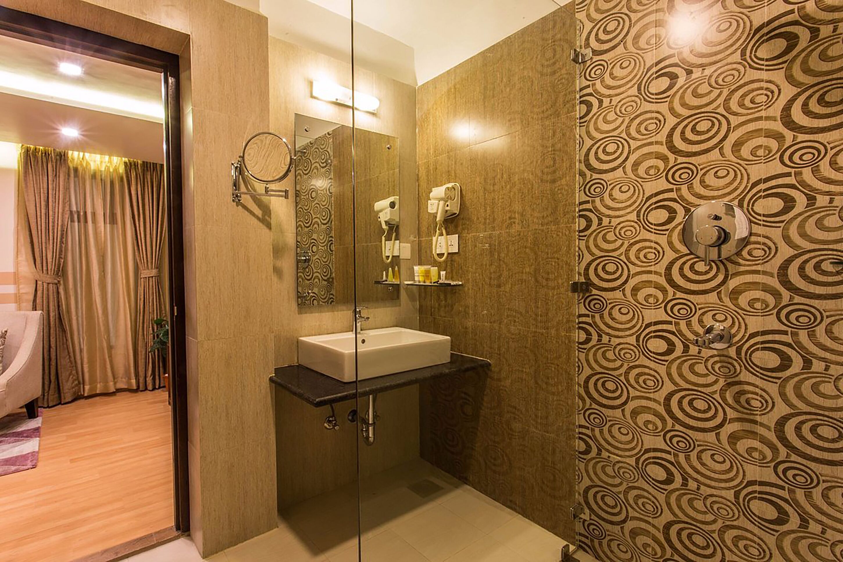 A modern bathroom with a glass shower enclosure, a vanity with a sink, and a patterned wall.