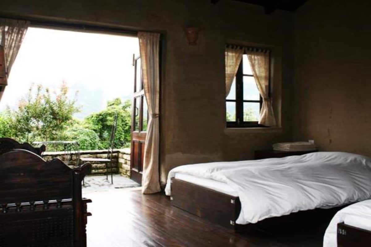 A room with a wooden bed, a small table, and a window with curtains.